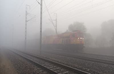 श्रीमाधोपुर में कोहरे के बीच दिन में लाइट जलाकर गुजरती ट्रेन। 