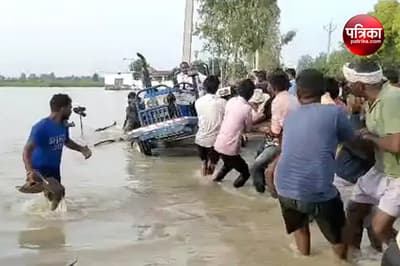 बाढ़ के पानी में फंसे ट्रैक्टर को निकालने की जद्दोजहद करते स्थानीय लोग